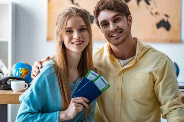 A man and woman smiling while holding their passports, ready for an exciting journey together.
