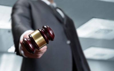 (In the image it can be seen a businessman is holding a gavel in his hand symbolising commercial dispute and litigation)