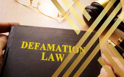 Close-up of a book titled "DEFAMATION LAW" next to a gavel and glasses.